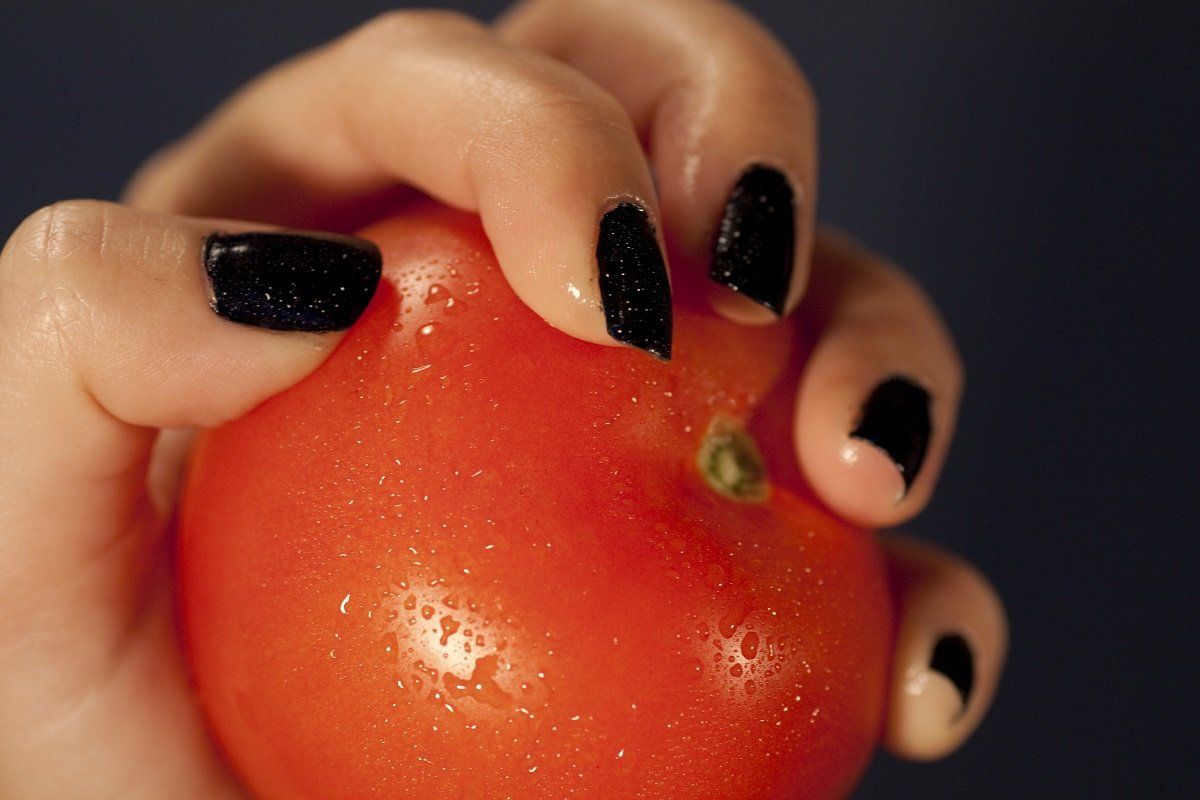 View of a woman hands holding a red tomatoe.