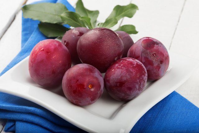 Сливы в тарелке / Fresh plums in bowl on white wooden background. Selective focus.