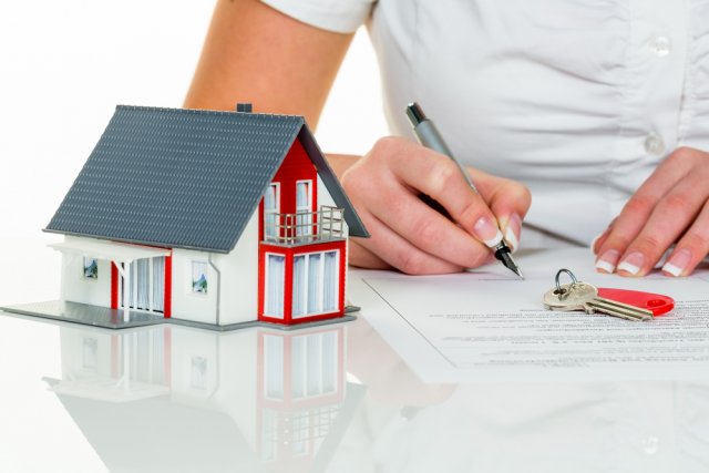 a woman signs a purchase agreement for a house in a real estate agent.