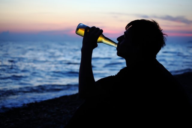 человек пьет на берегу
