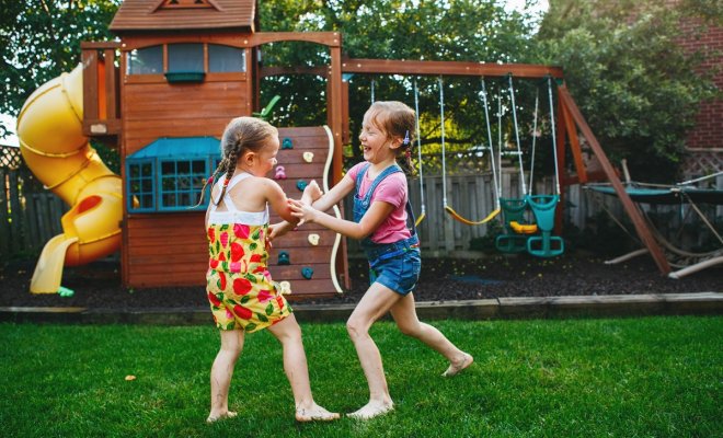 : Portrait of two little girls sisters fighting on home backyard. Friends girls having fun. Lifestyle candid family moment of siblings quarreling playing together. 